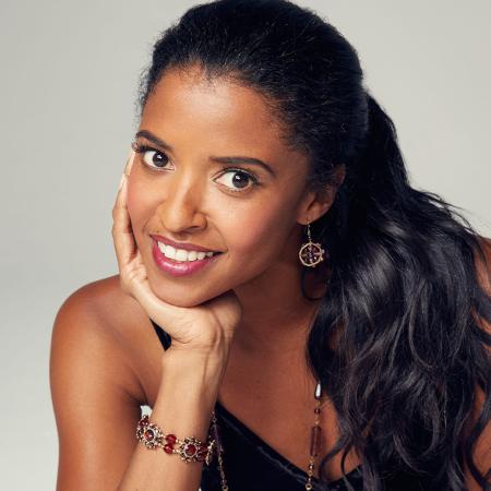 Renée Elise Goldsberry smiling with her head cupped in one palm.