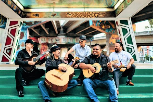 Members of Jarabe Mexicano sitting on steps holding their instruments.